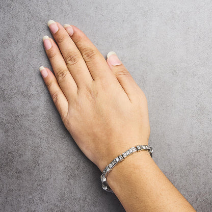 White metal bracelet with round white gemstones in a channel setting, shown worn on a model's wrist, top view angle.