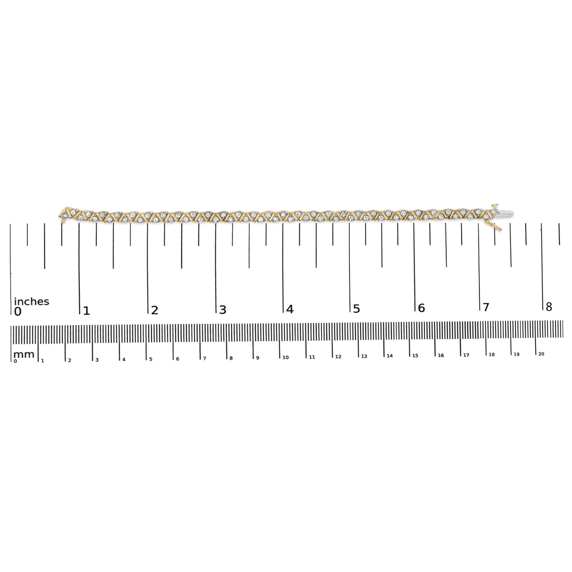 Yellow metal bracelet with round white gemstones in three-prong settings placed in a zigzag pattern, displayed flat on a ruler for size reference, shot from above.