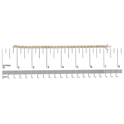 Yellow metal bracelet with round white gemstones in three-prong settings placed in a zigzag pattern, displayed flat on a ruler for size reference, shot from above.