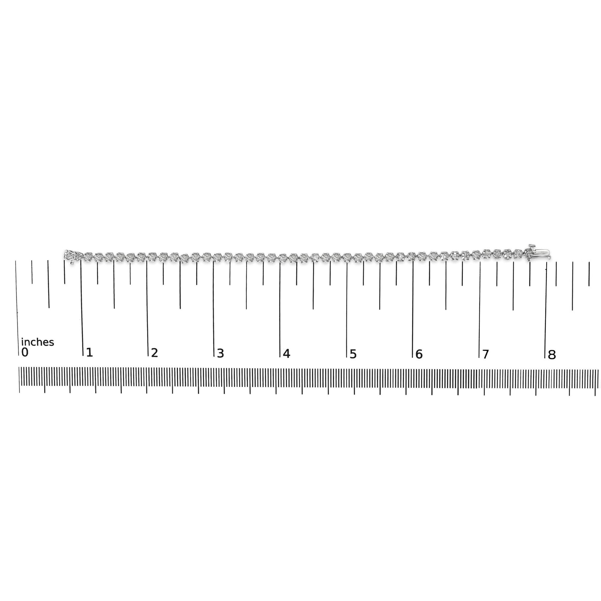 White metal bracelet with round white gemstones in prong settings, laid flat on a ruler for size reference, shot from above.