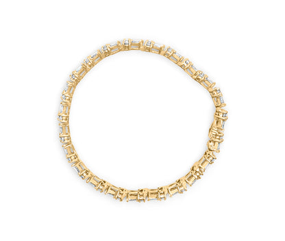 Top-down view of a yellow bracelet featuring white round gemstones in prong settings alternating with white baguette gemstones in channel settings.