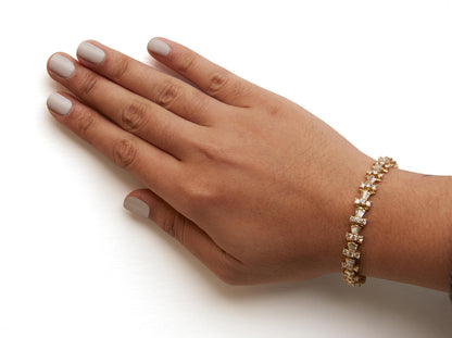 Close-up side angled shot of a yellow bracelet with alternating round and baguette white gemstones in prong and channel settings, worn on a model's wrist.