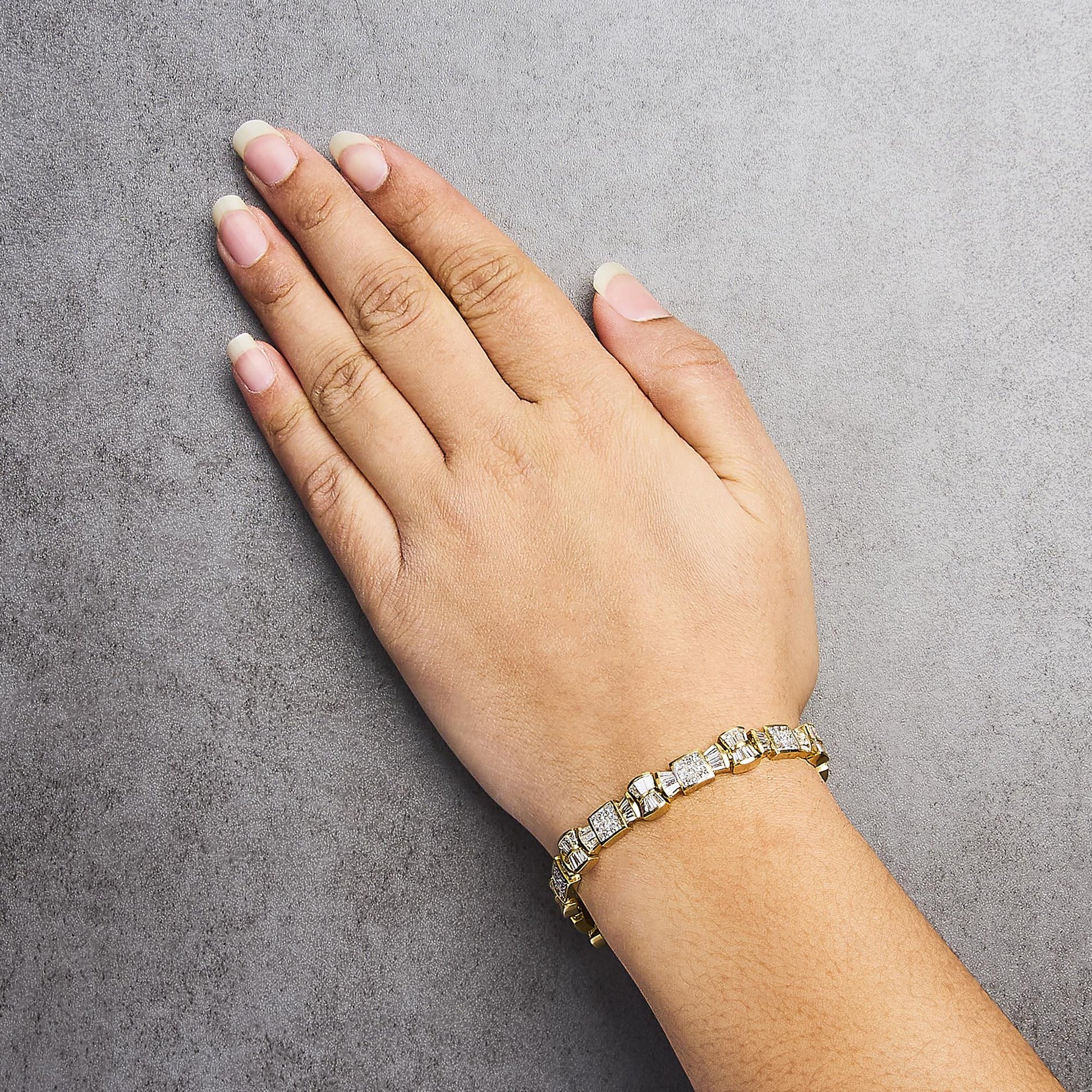 Yellow bracelet with alternating square and rectangular white gemstones in channel and invisible settings, shown on a model's wrist from a top angle.