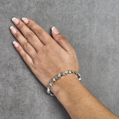 White metal bracelet with alternating baguette shaped and princess shaped white gemstones, shown worn on a model's wrist, top-down angle.