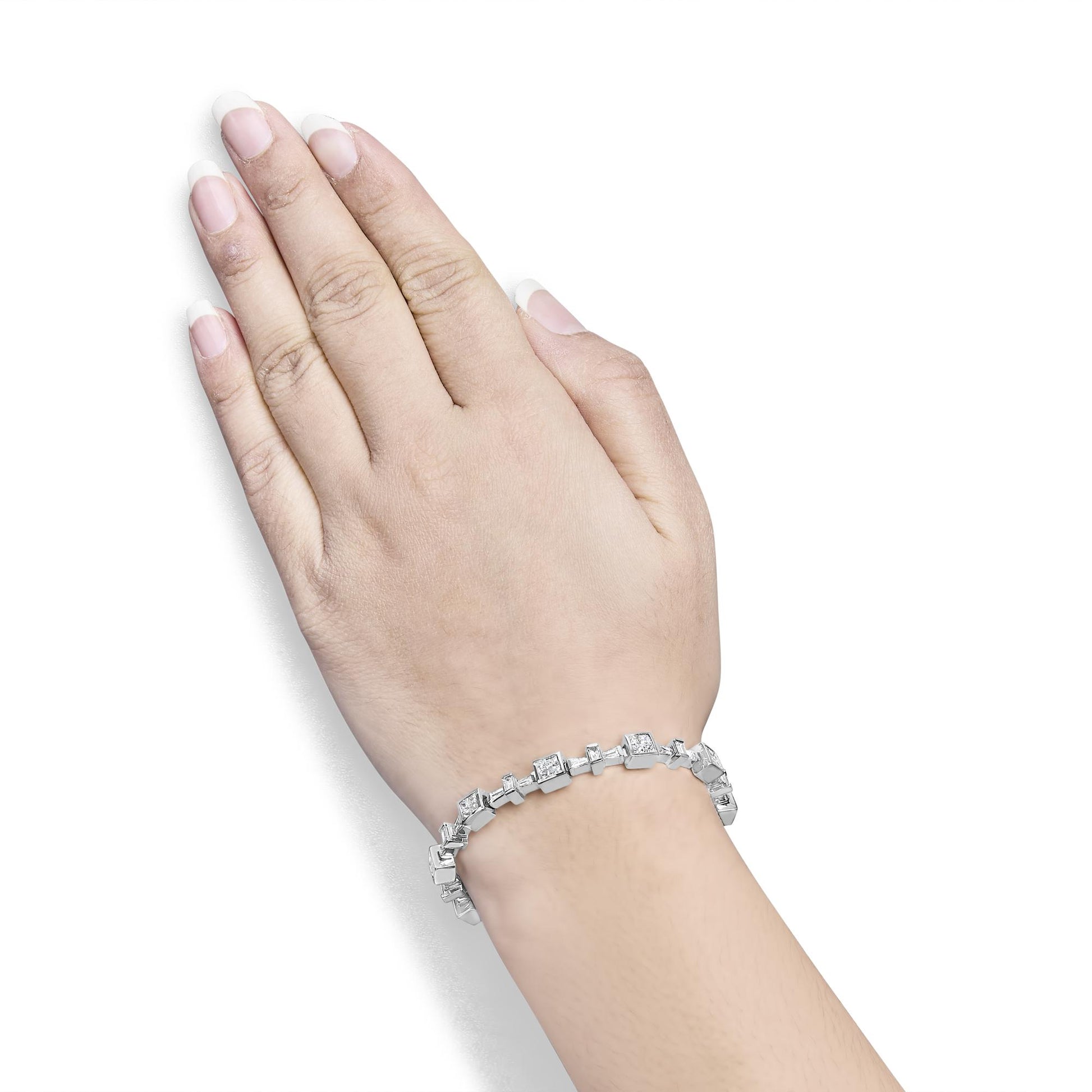 White metal bracelet with alternating princess and baguette shaped white gemstones, shown worn on a model's wrist, shot from above at an angle.