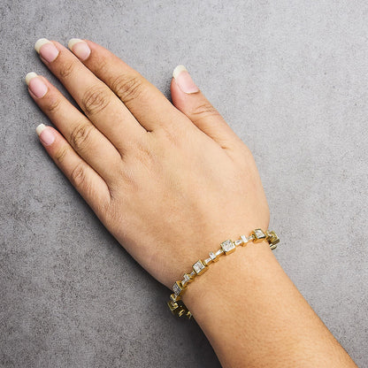 Yellow metal bracelet with alternating white baguette and princess-shaped gemstones in channel and invisible settings, worn on a model's wrist, shown from top angle.