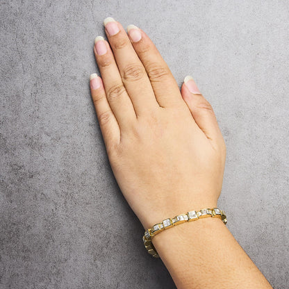 Bracelet with alternating channel-set baguette and invisible-set princess white gemstones in yellow metal, shown worn on a model's wrist from an overhead angle.