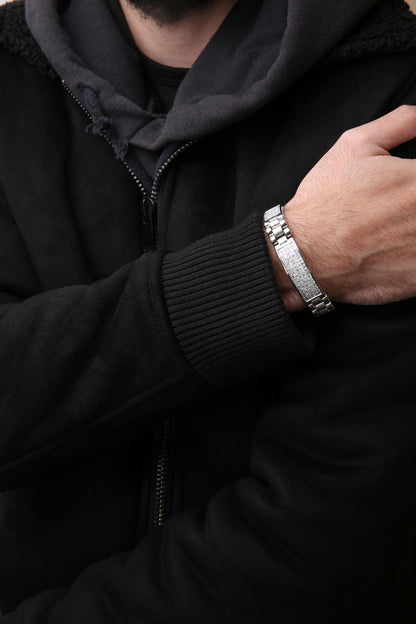 Close-up angled view of a white metal bracelet with two rectangular panels set with white princess-shaped gemstones in an invisible setting, worn on a model's wrist.