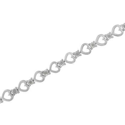 Diagonal close-up of a white metal bracelet with alternating heart shapes and round white gemstones in miracle settings.