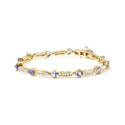 Yellow metal bracelet with alternating rectangular sections featuring white round gemstones in channel setting and blue trillion-shaped gemstones in prong setting, shown in a front angled view.