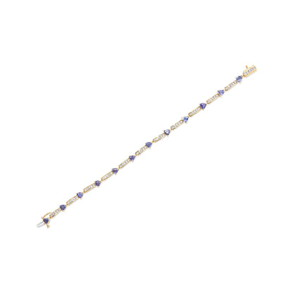 Yellow metal bracelet with alternating rectangular segments of channel-set white round gemstones and prong-set blue trillion gemstones, shown in a diagonal top-down view.