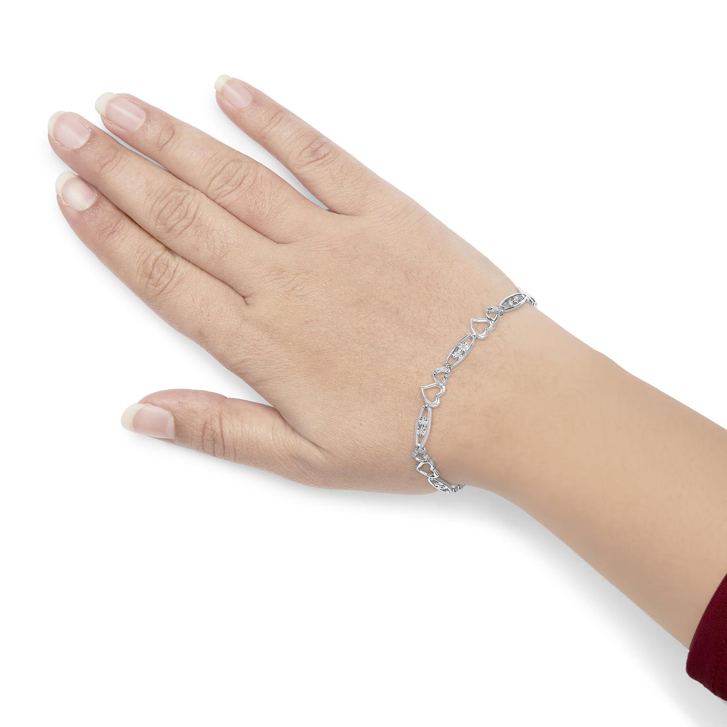 White metal bracelet with alternating heart shapes and oval links set with round white gemstones, shown on top of a model's wrist with hand angled downward.