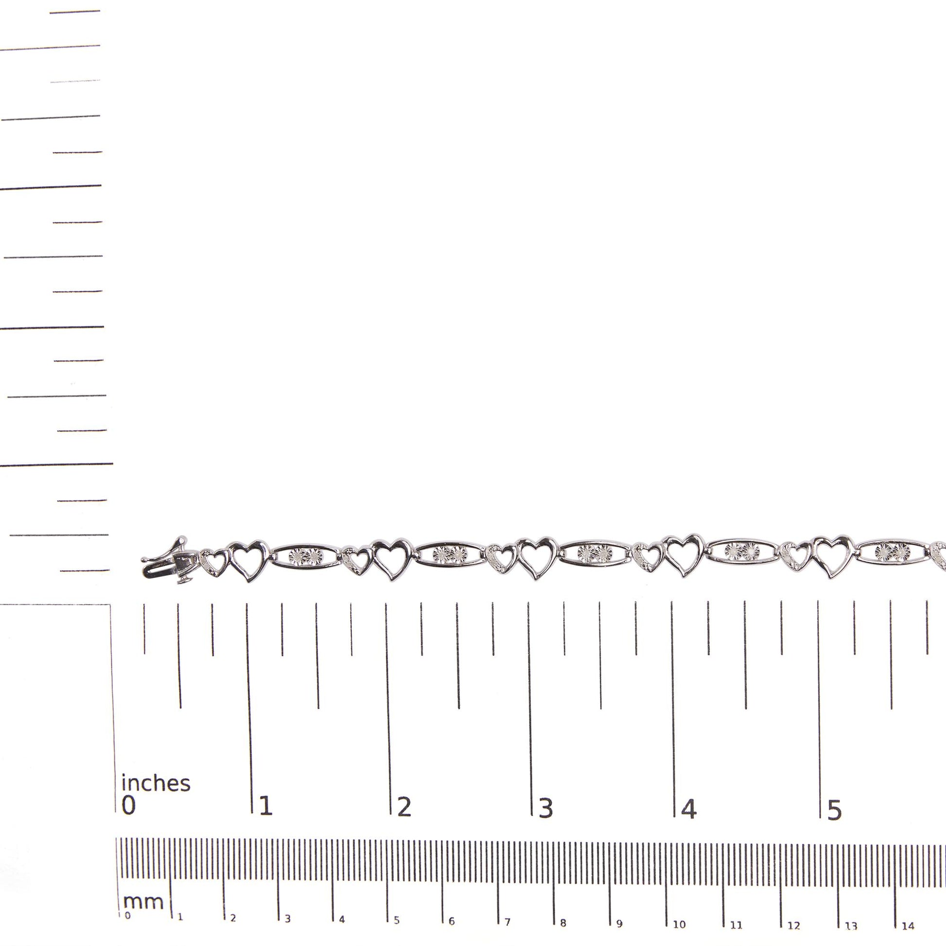 White metal bracelet with alternating open heart shapes and oval links set with round white gemstones, shown flat on a ruler for size reference, top-down view.