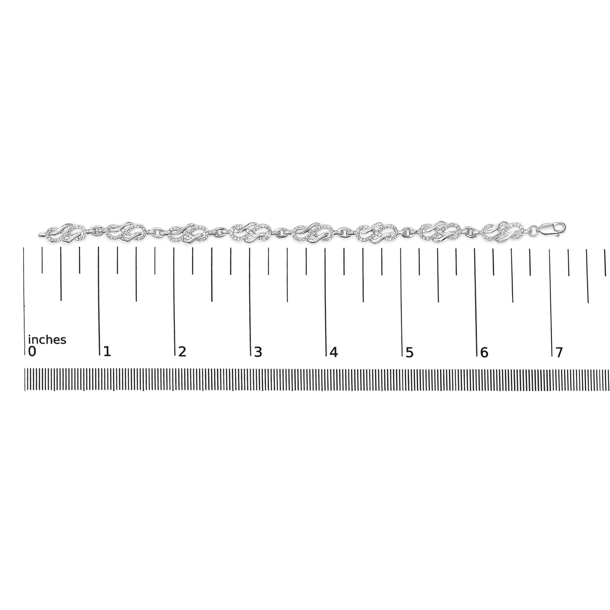 White bracelet with intertwined design links pavé set with round white gemstones, shown flat on a ruler for scale, top-down angle.