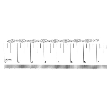 White bracelet with intertwined design links pavé set with round white gemstones, shown flat on a ruler for scale, top-down angle.