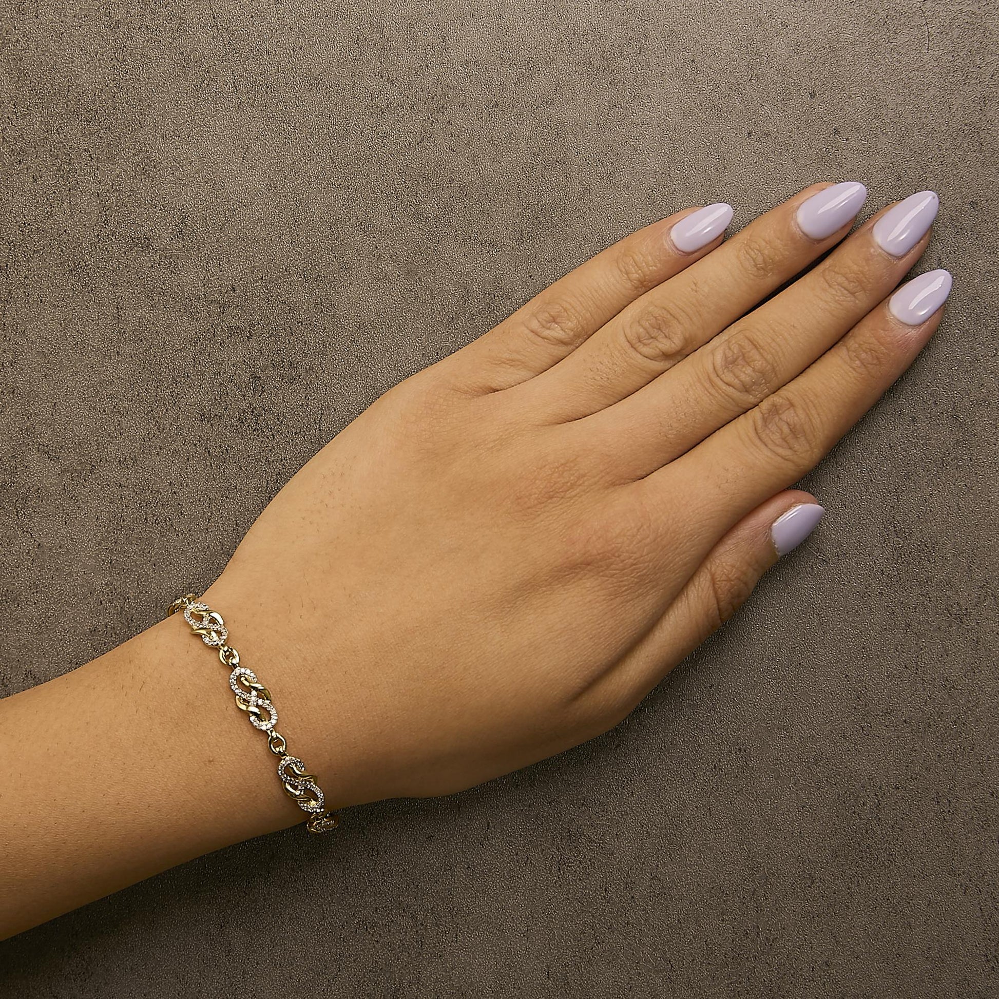 Bracelet with alternating curved links adorned with white pave-set round gemstones shown worn on a model's wrist, photographed from above at an angle.