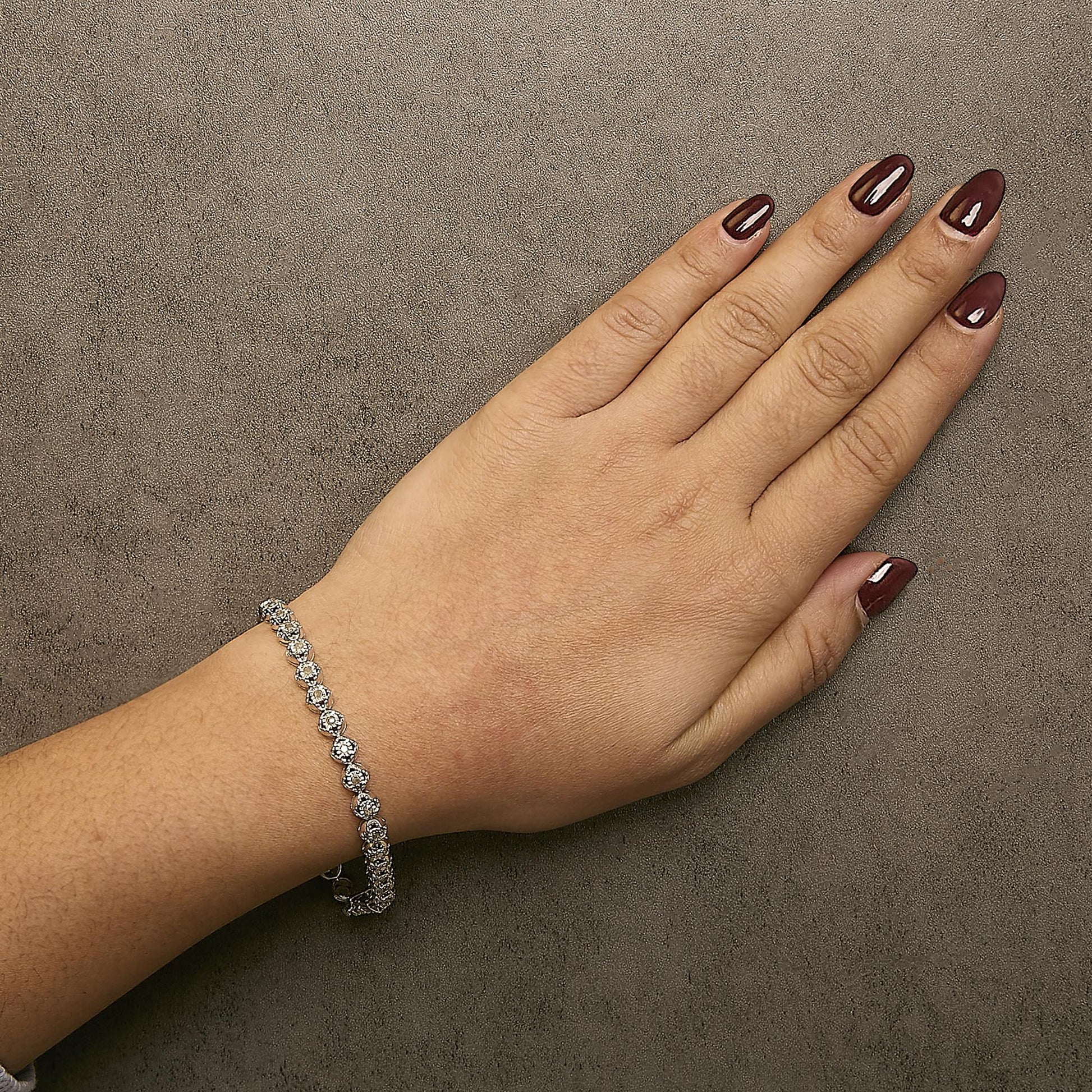 White metal bracelet with round prong-set white gemstones, worn on a model's wrist, shown from above.