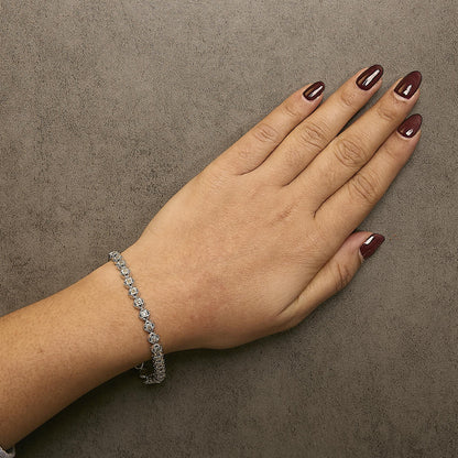 White metal bracelet with round prong-set white gemstones, worn on a model's wrist, shown from above.