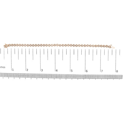 Rose-colored bracelet with round white gemstones in miracle setting, laid flat on a ruler for size reference, top-down view.