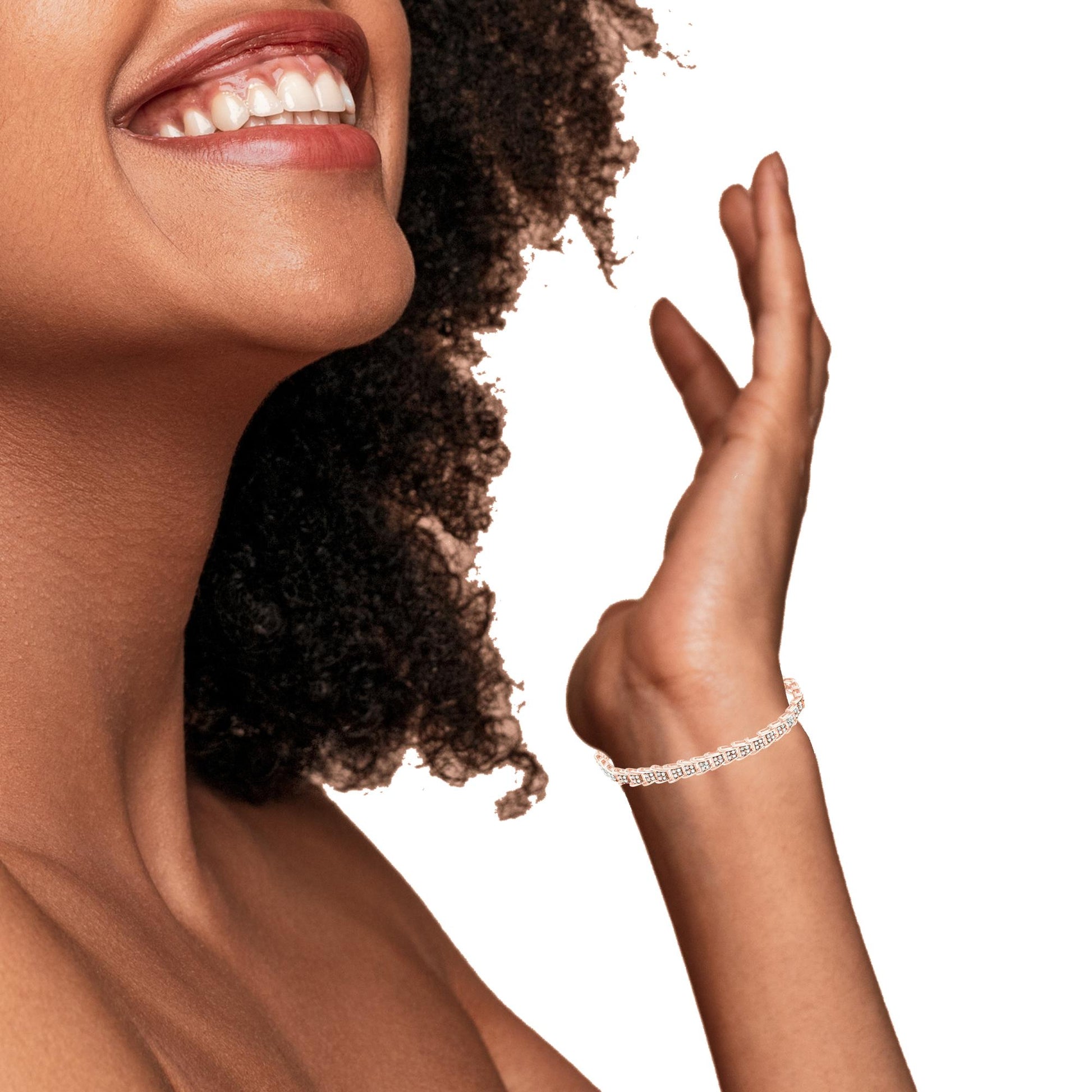 Close-up side view of a smiling model wearing a rose-colored bracelet with round white gemstones in prong settings on their wrist.