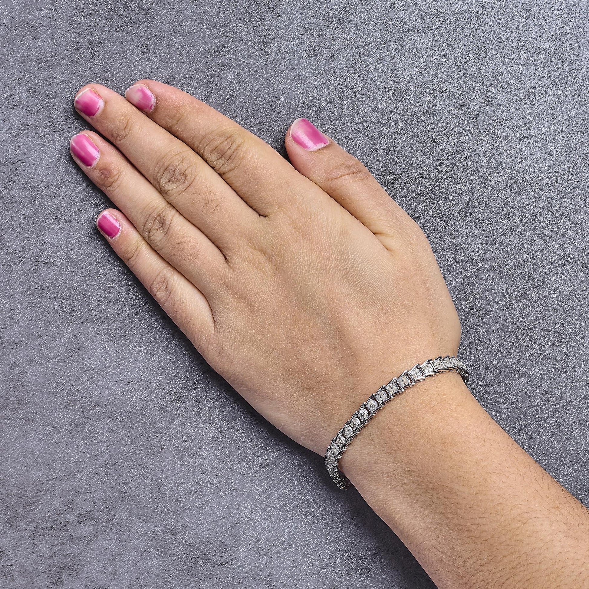 White metal bracelet with round white gemstones in prong settings, shown on a model's wrist from a top angle.