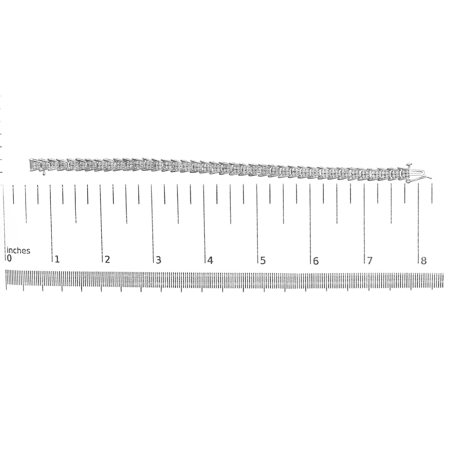 Top-down view of a white metal bracelet with round white gemstones in prong settings, laid flat on a ruler for size reference.