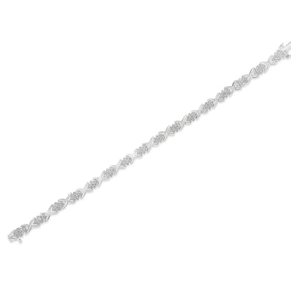 Diagonal close-up of a white metal bracelet featuring round white gemstones in prong settings alternating with crisscross metal links.