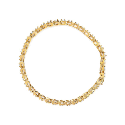 Top-down view of a yellow metal bracelet with round white gemstones in prong settings all around.