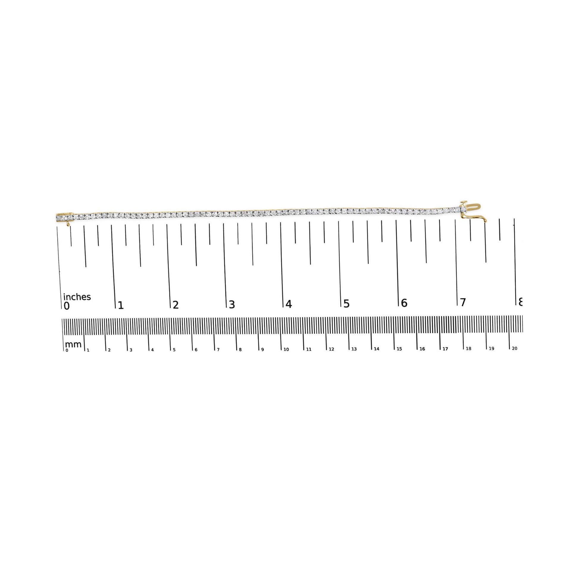 Yellow bracelet with round brownish gemstones in 4-prong setting, laid flat on a ruler for size reference, top-down view.