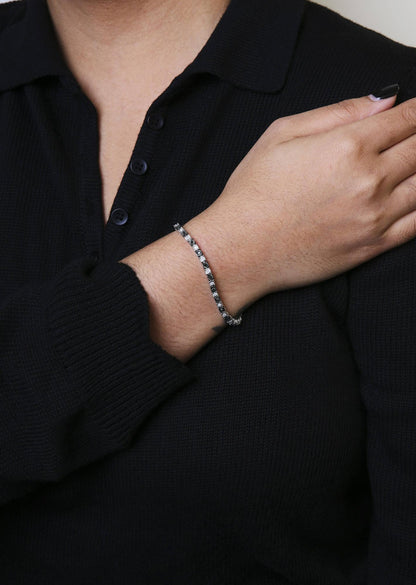 White metal bracelet with alternating black round and white rose-shaped gemstones in miracle setting, shown on a model's wrist, front angle.