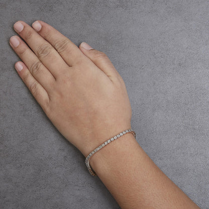 Rose metal bracelet with round white gemstones in miracle setting, shown from above on a model's wrist.
