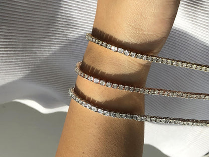 Close-up image of a rose-colored bracelet with round white gemstones in miracle setting, worn on a model’s wrist at an angled side view.