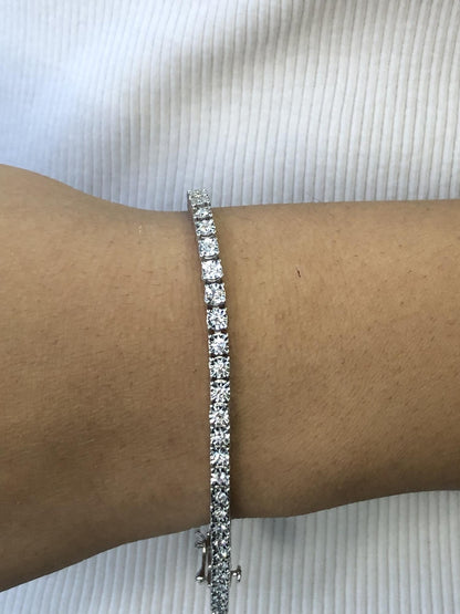 White metal bracelet with round white gemstones in a miracle setting, shown on a model’s wrist from a side angle.