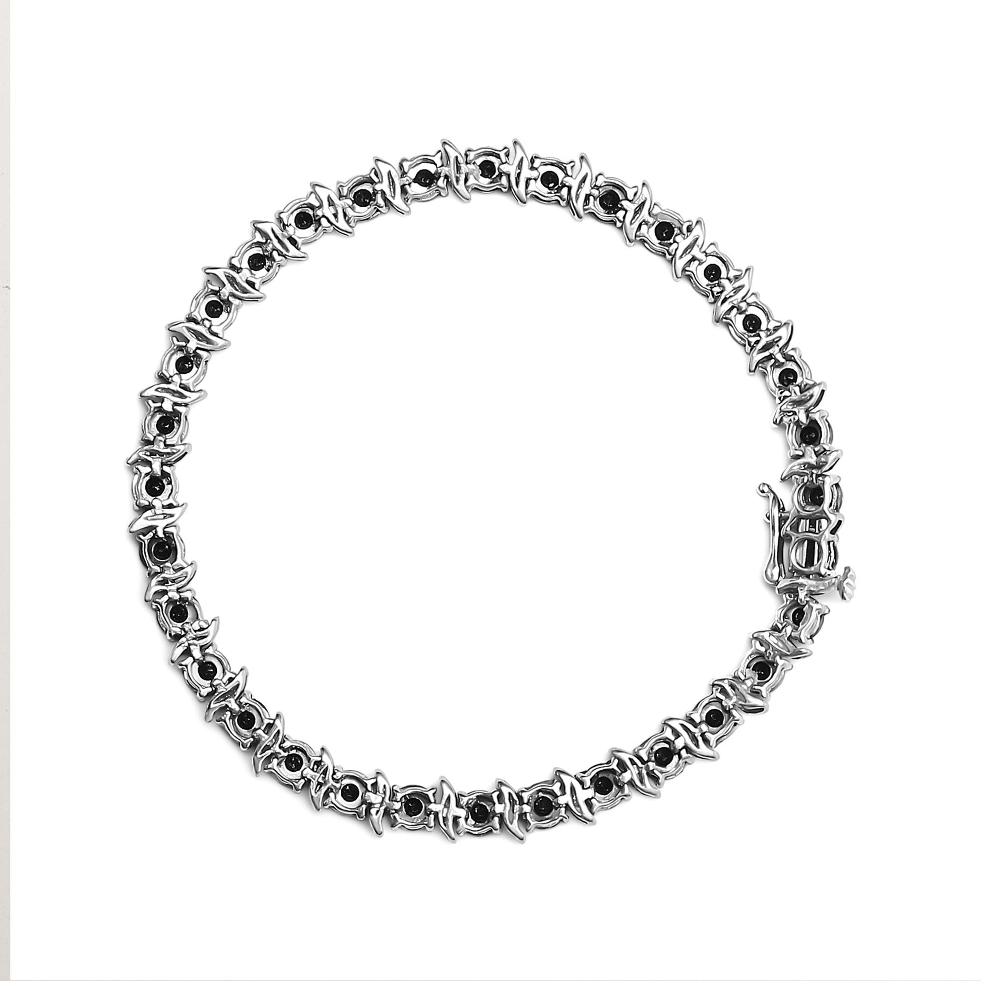 Top-down view of a white metal bracelet with round black gemstones in miracle settings encircling the entire piece.