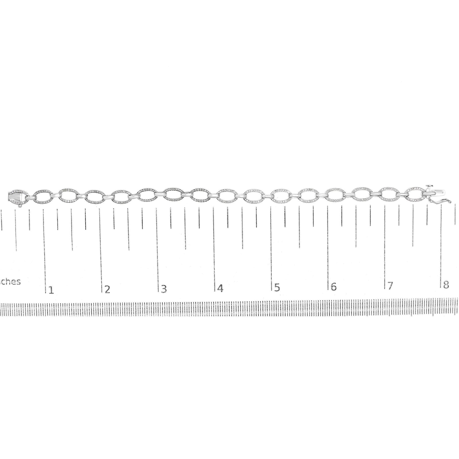 White metal bracelet with oval links set with round white gemstones in prong settings, laid flat on a ruler for size reference, top-down angle.