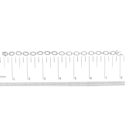 White metal bracelet with oval links set with round white gemstones in prong settings, laid flat on a ruler for size reference, top-down angle.