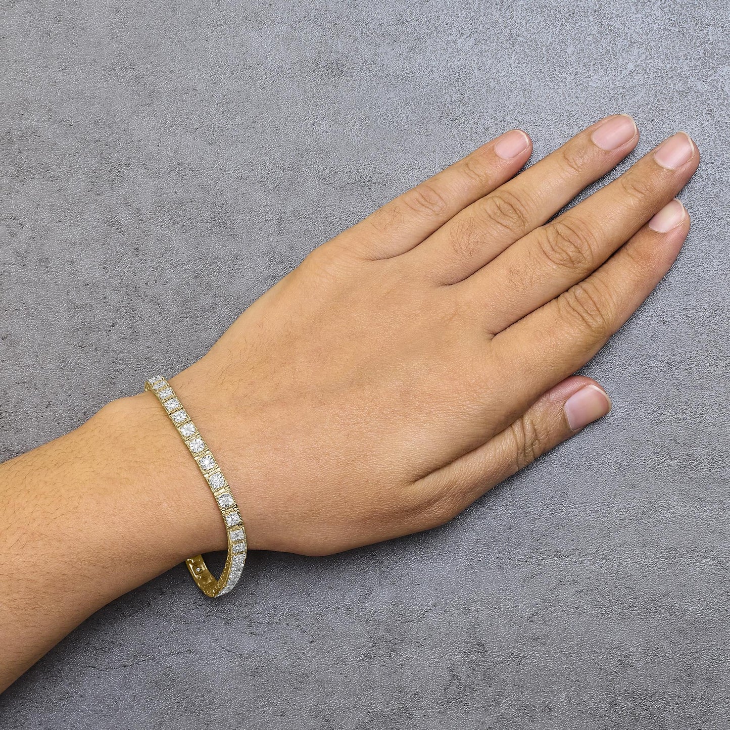 Yellow bracelet with round white gemstones in miracle setting, worn on a model's wrist, top-down angle.