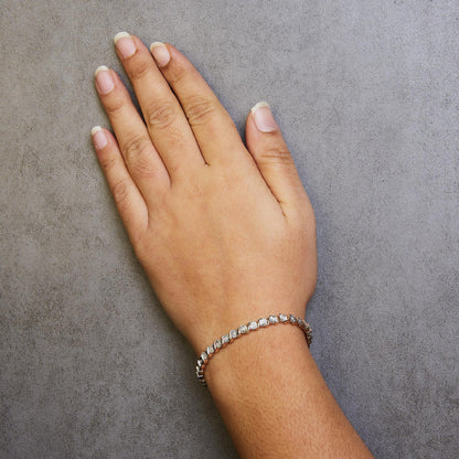 Rose-colored bracelet with round white gemstones in miracle setting on a model's wrist, top-down angle.