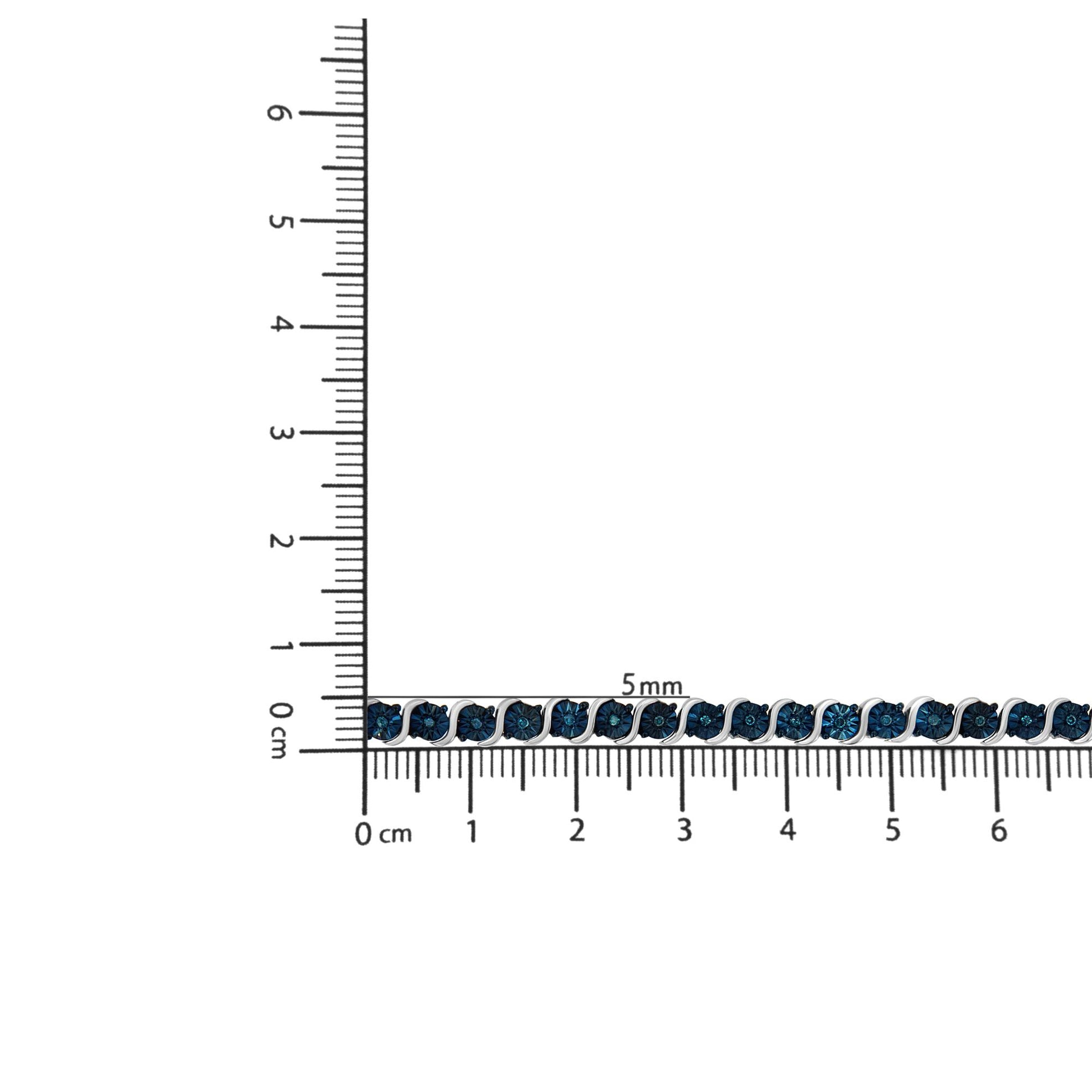 White metal bracelet with round blue gemstones in miracle settings laid flat on a ruler for size reference, top-down angle.