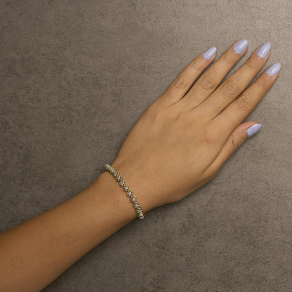 Yellow bracelet with round white gemstones in prong settings, shown on a model's wrist, top-down angle.