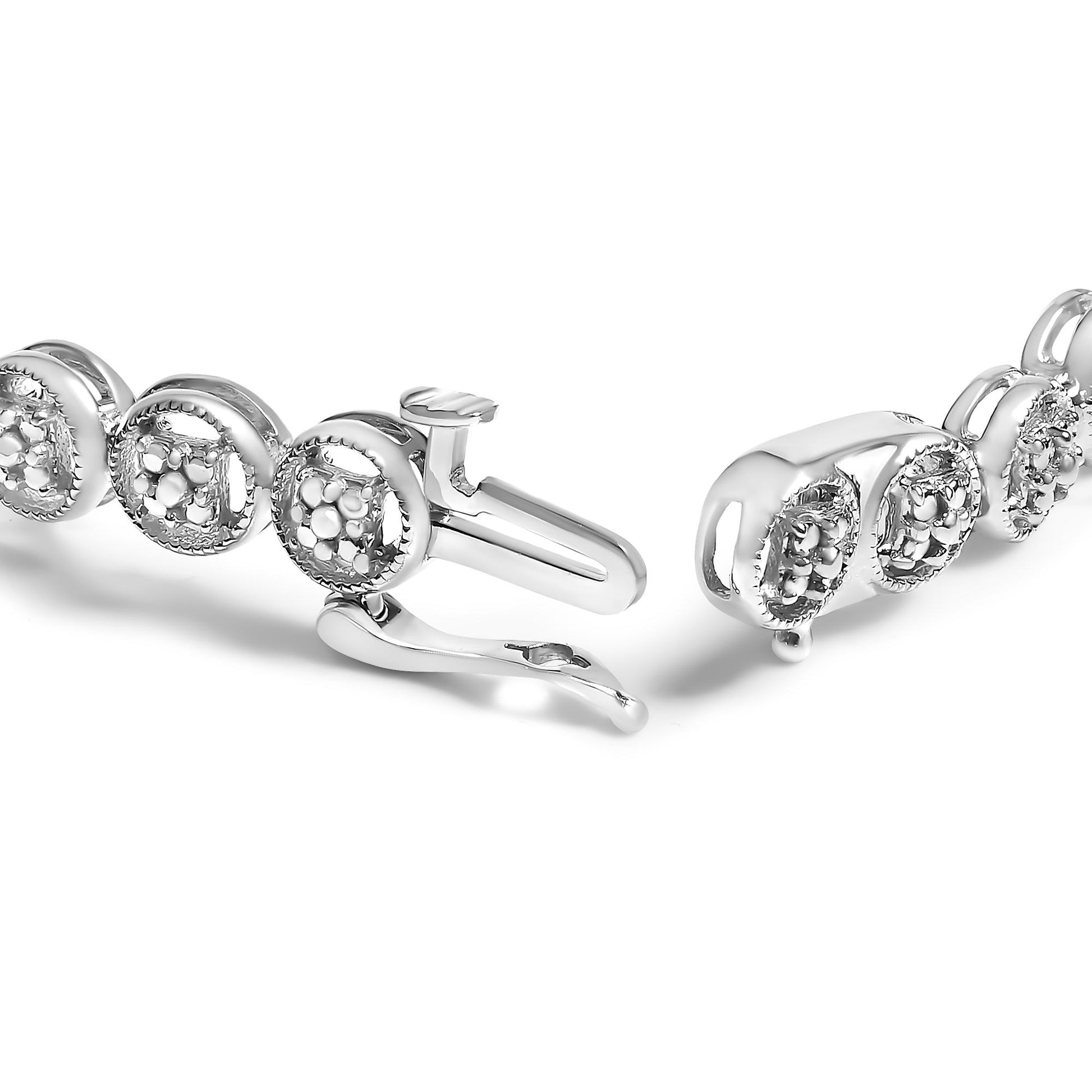 Close-up side angle of a white metal bracelet with round clusters of white gemstones in prong settings.