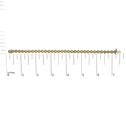 Top view of a yellow metal bracelet with round white gemstones in prong settings, placed on a ruler for size reference.