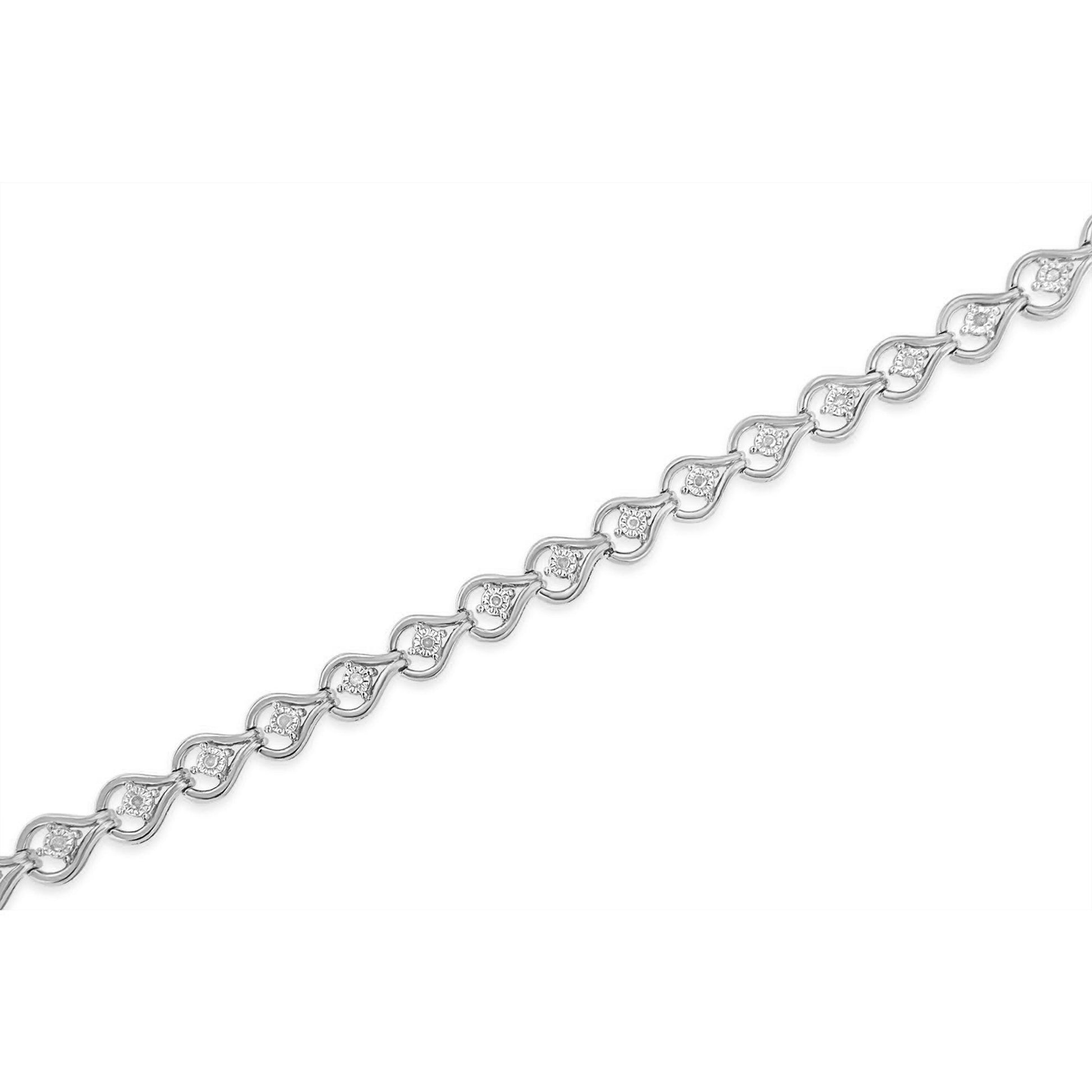 White metal bracelet with a repeating wave-shaped design each set with a round white gemstone, shown in a close-up angled view.