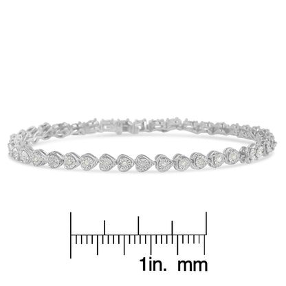 White metal bracelet with heart-shaped links each set with a round white gemstone in miracle setting, shown on a scale, front angled view.