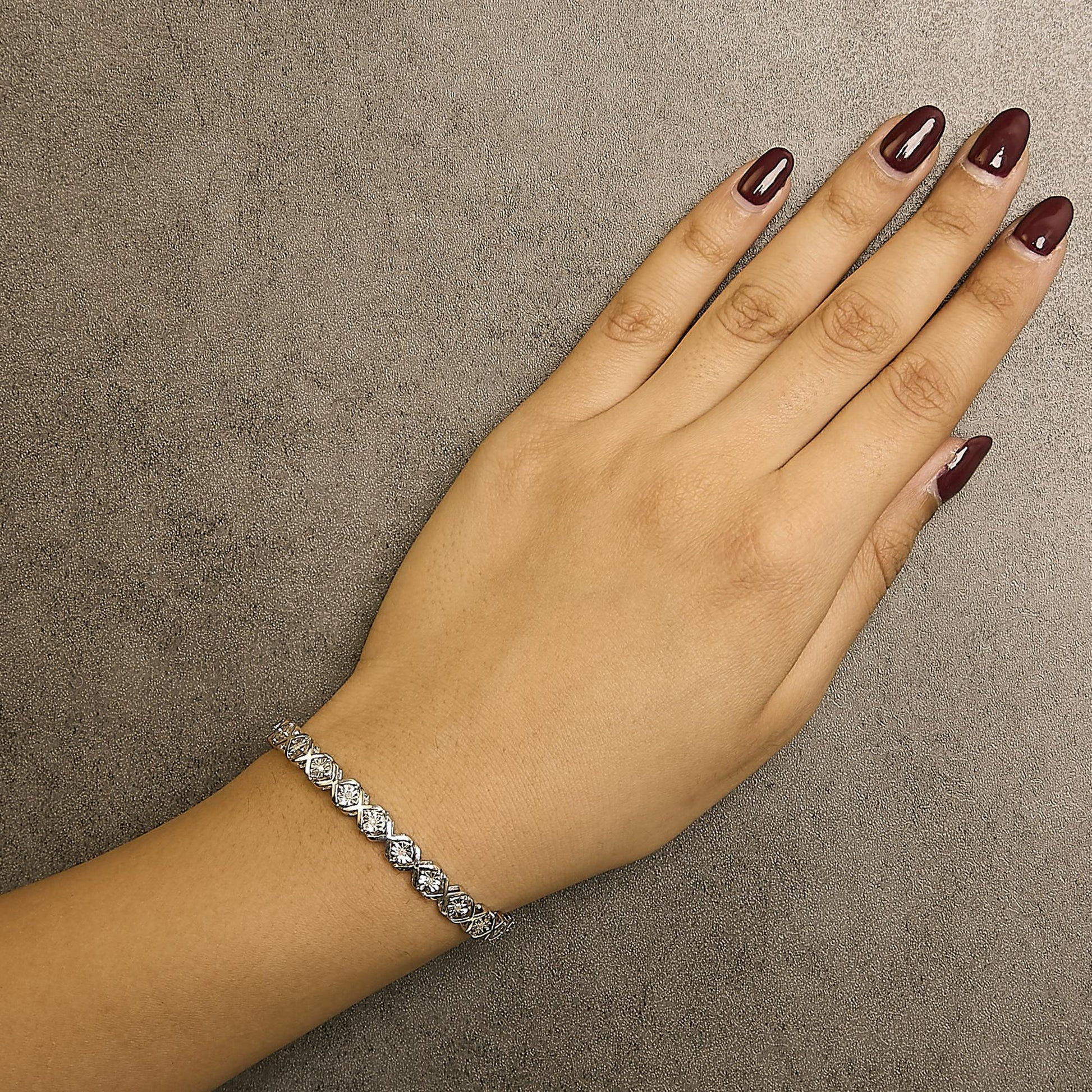 White metal bracelet with round white gemstones in miracle setting, shown on a model's wrist from a top-down angle.