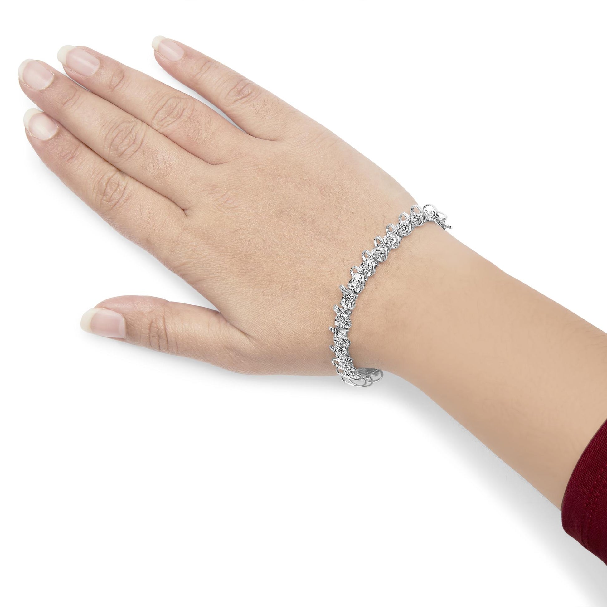White metal bracelet with round white gemstones in miracle and prong settings, worn on a model's wrist, shown from top angle.