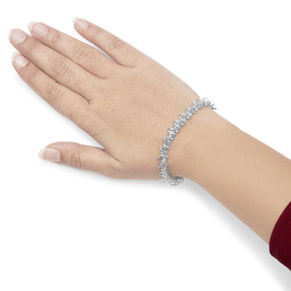White metal bracelet with round white gemstones in miracle and prong settings, worn on a model's wrist, shown from top angle.