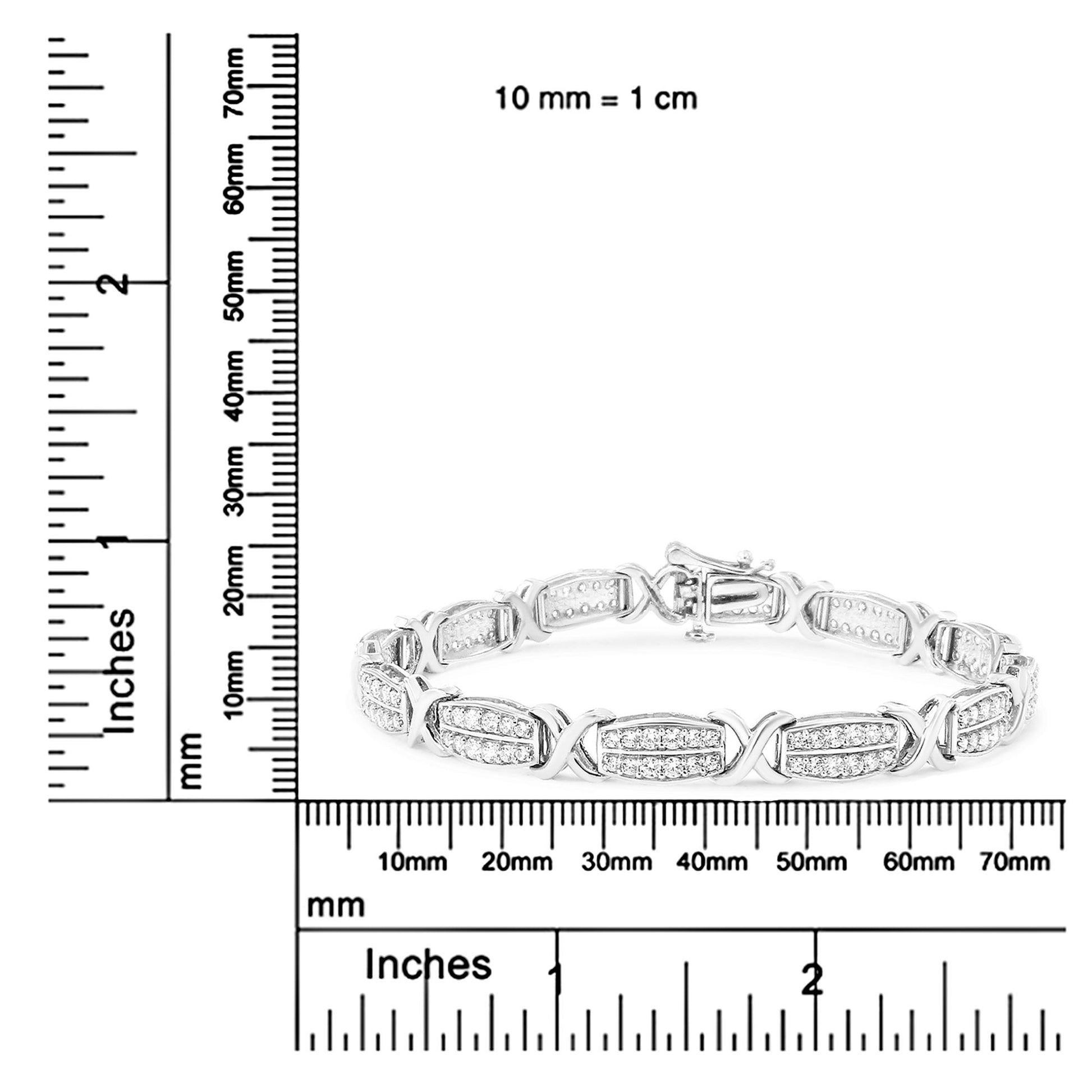White metal bracelet with alternating oval links and X-shaped connectors, each oval link set with pave white round gemstones, shown in a front angled view on a ruler for size reference.