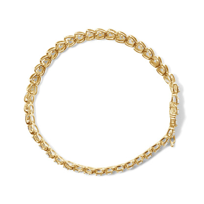 Top-down view of a yellow metal bracelet with round white gemstones in prong settings along the links.