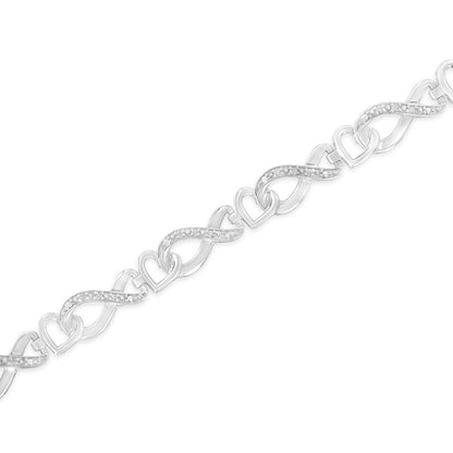 White metal bracelet with alternating heart and infinity-shaped links; infinity links feature white gemstones in pave setting, shown in a diagonal close-up view.